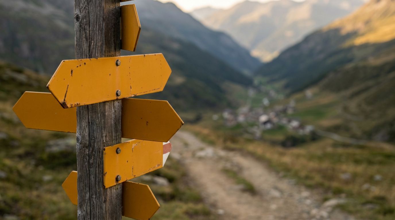 Yellow direction plates on a weathered post above a valley trail, late-afternoon light